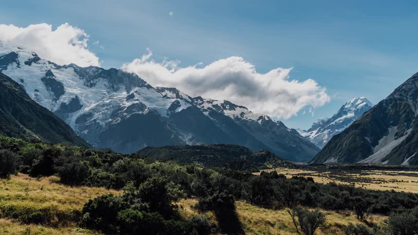 Clouds are drifting across mountain peaks during the day
