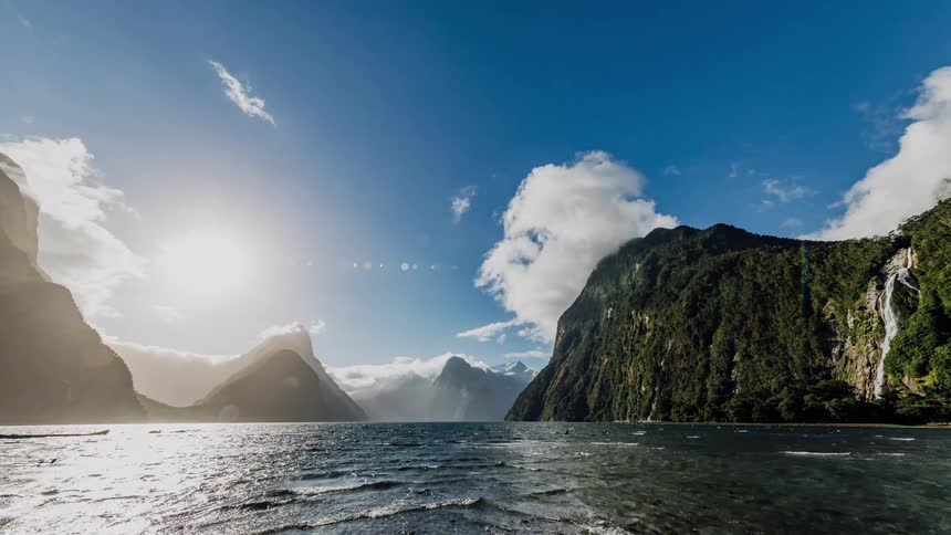 Clouds billow over mountains and water flows beneath