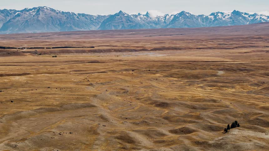 Clouds are casting shadows on tundra in a mountain setting through the day