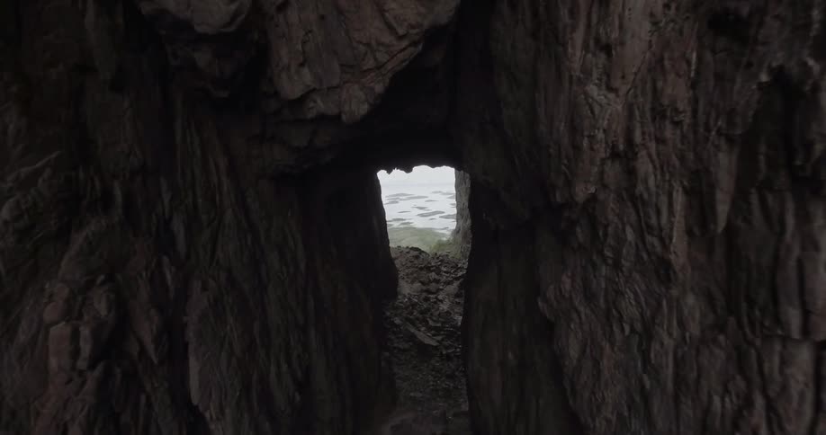 Dark tunnel of rock leading out to the sea