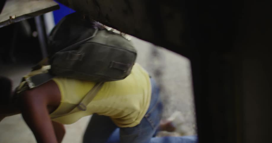 A girl crawls under the door of a warehouse