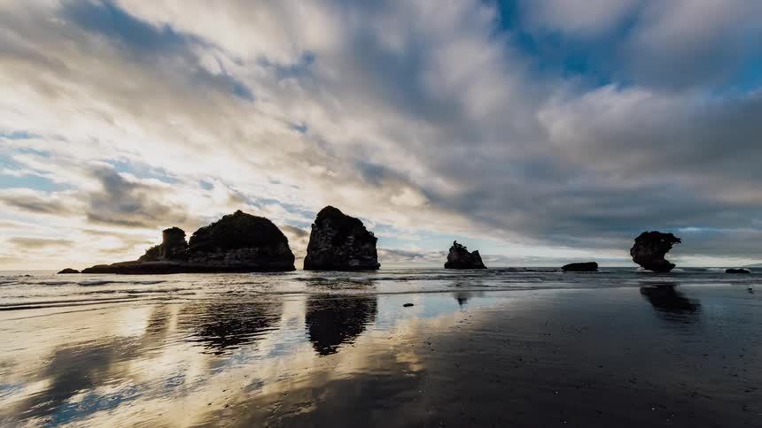 The ocean water reflects the rocks and the sky