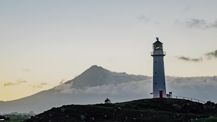 A lighthouse in front of a mountain