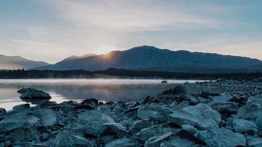 Steam rises off a lake at sunrise