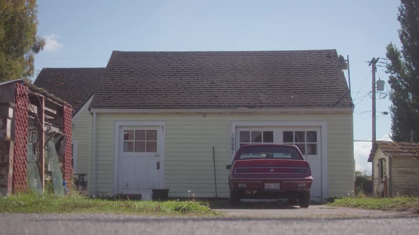 A late model american car is sitting outside a house on a sunny day