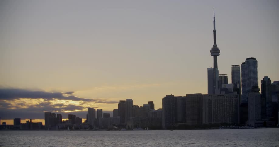 The sun sets behind an ocean front Toronto city skyline
