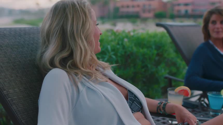 Two women are laying by a pool talking