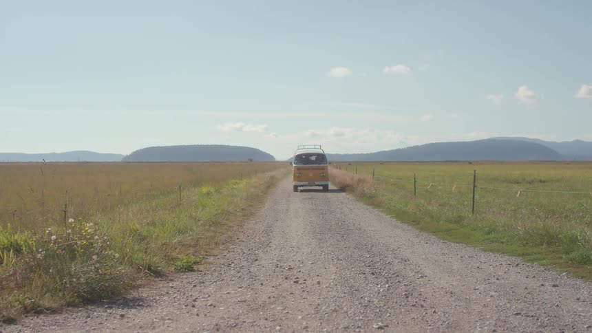 A van drives down a gravel road on a sunny day