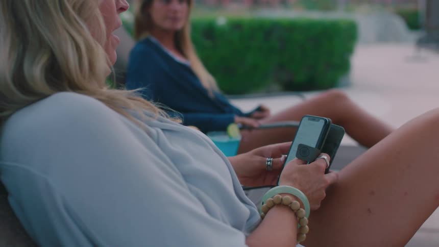A woman sits outside browsing on her phone