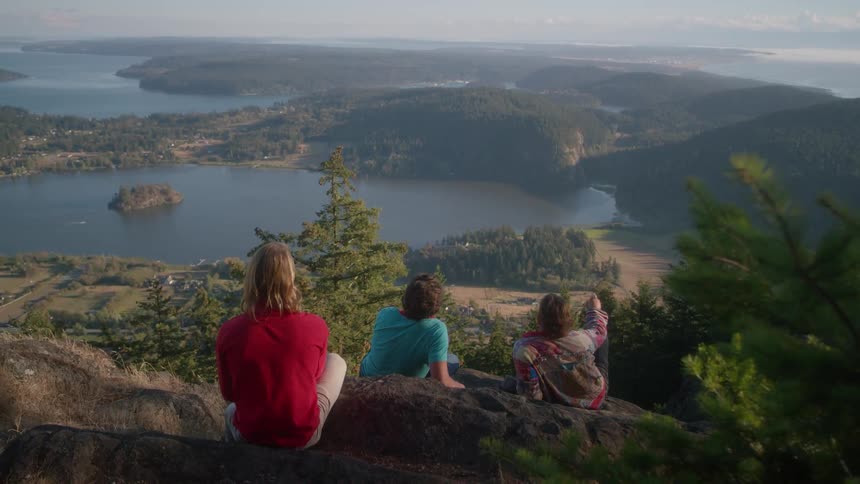 Boys sit on a rocky ledge overlooking the water below