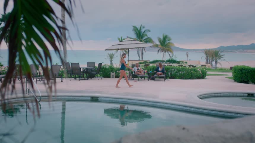 A woman walks past two others sitting by the pool