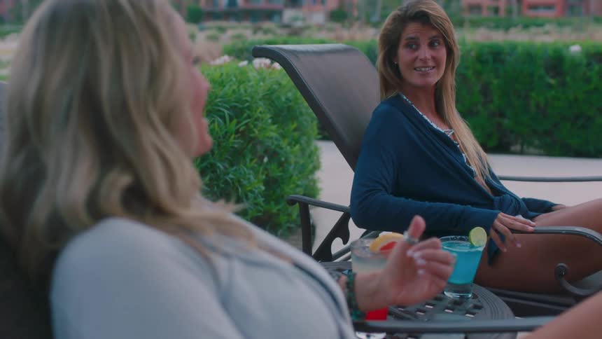 Two women sit in lawn chairs outside talking