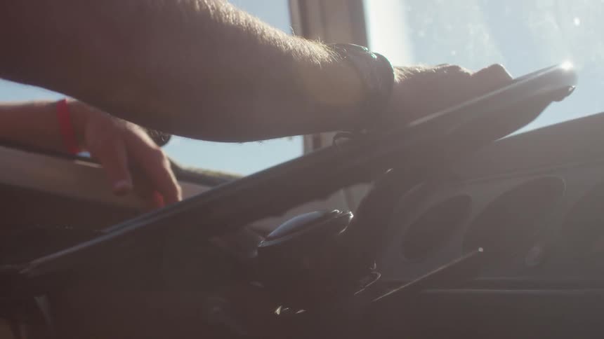Man's arm on a steering wheel on a sunny day