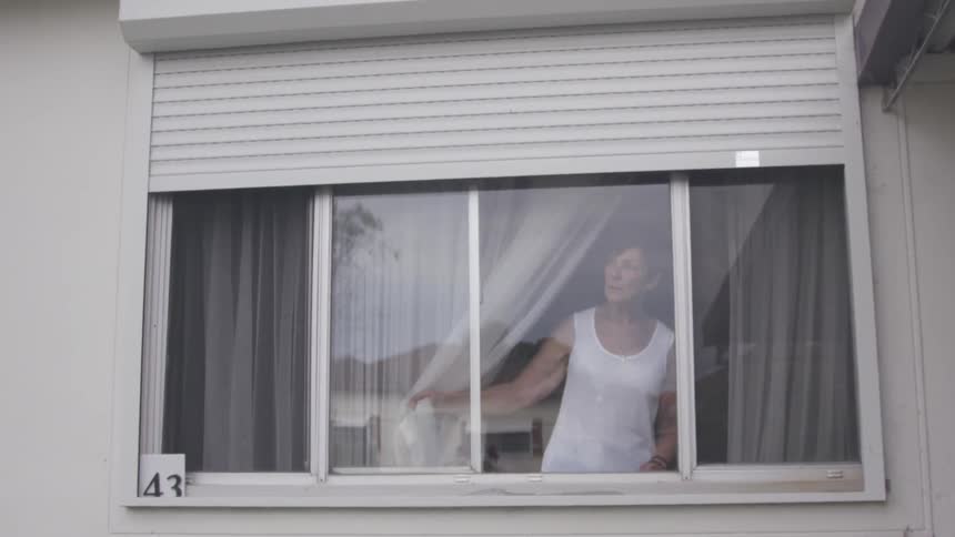A woman looks out a window