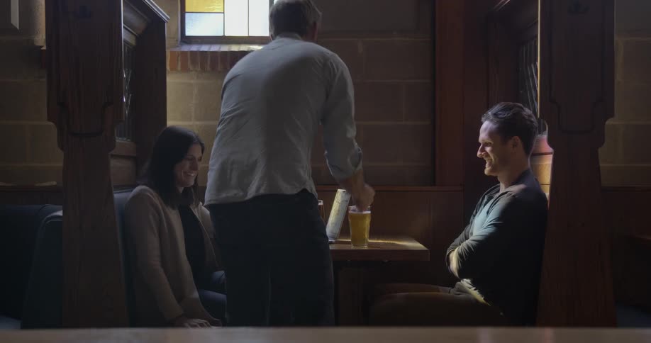 A man and woman in a restaurant have their drinks brought to them