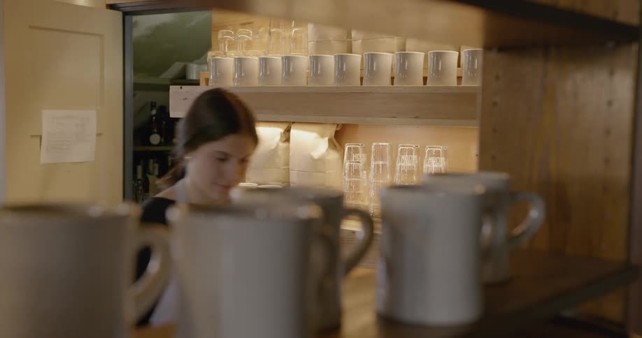 A woman is turning on the lights in a coffee shop