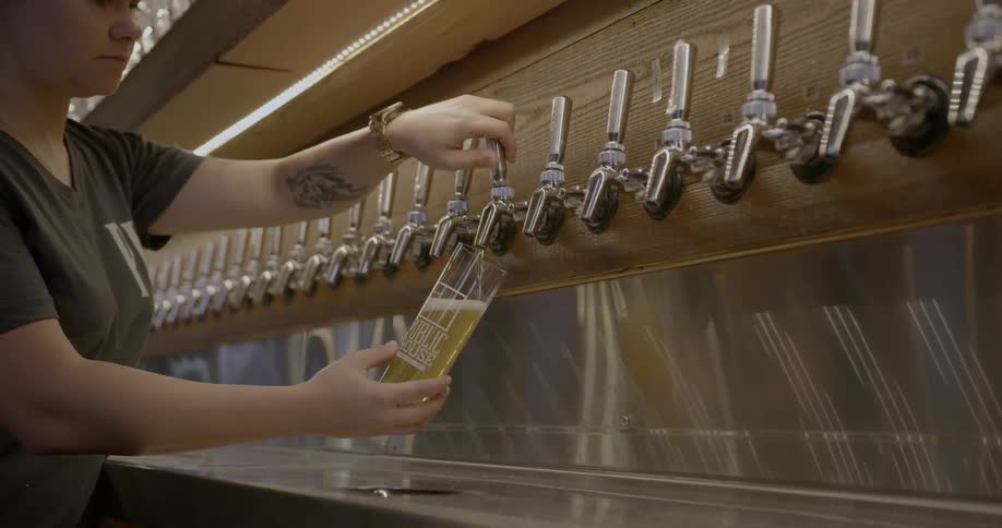 Woman pours beer into a glass in a bar