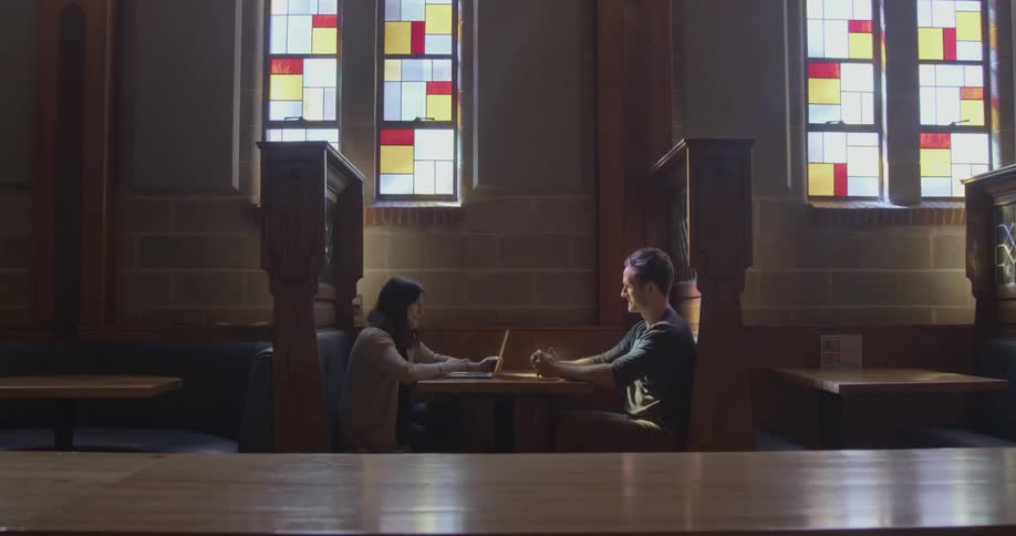 Two people are sitting down at a restaurant with stain glass windows