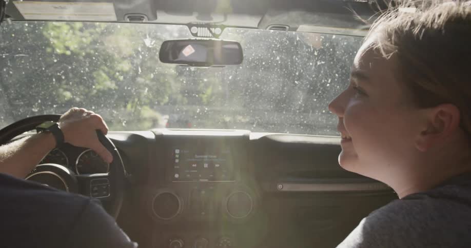 A father and daughter talk as they drive in a Jeep