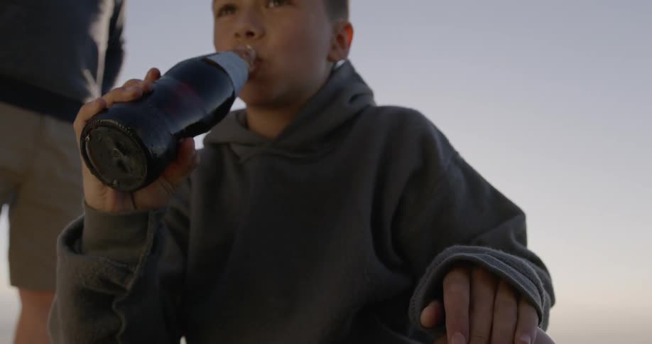 Boy drinks a glass bottle of soda