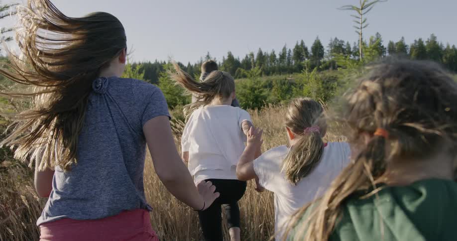Children are running through field of weeds on windy day