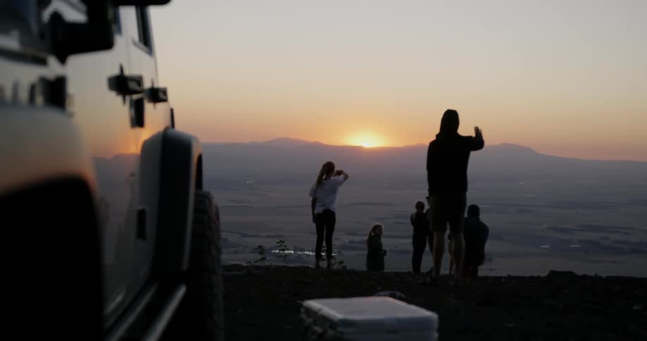 A group of children wave from the top of a mountain