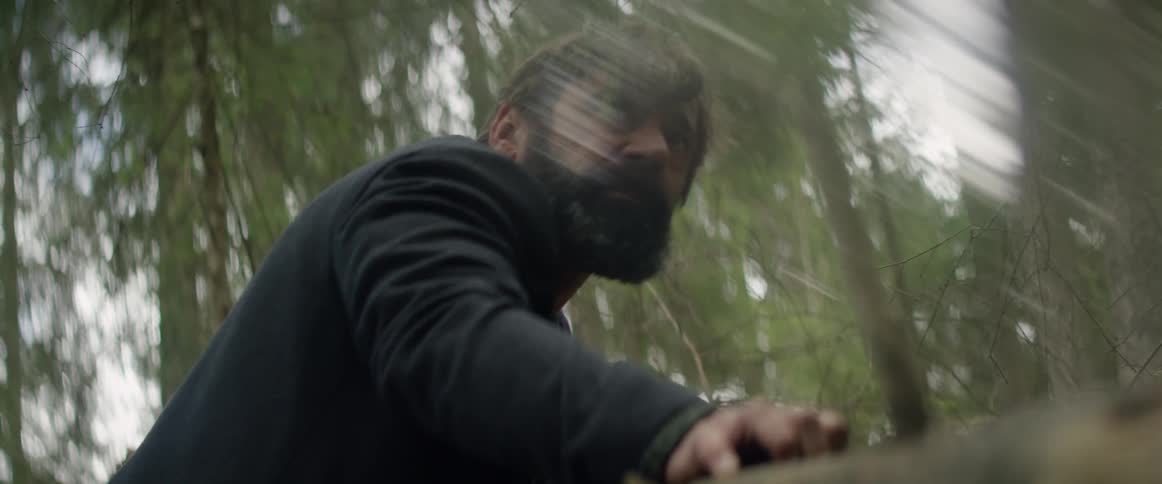 A man leans against a fallen tree in the woods