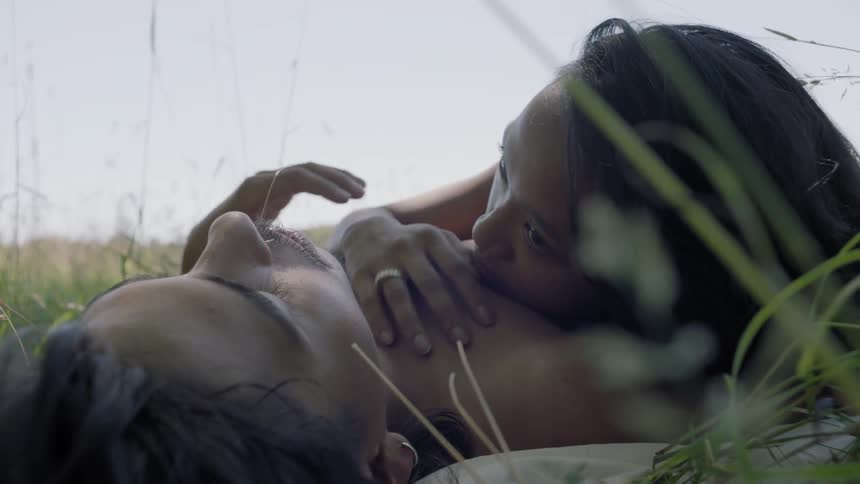 A man and woman lay together outside in the grass