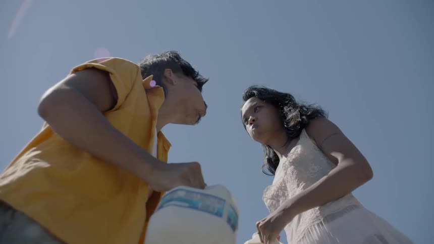 A man and woman are drinking from gallon jugs of milk outside on a sunny day