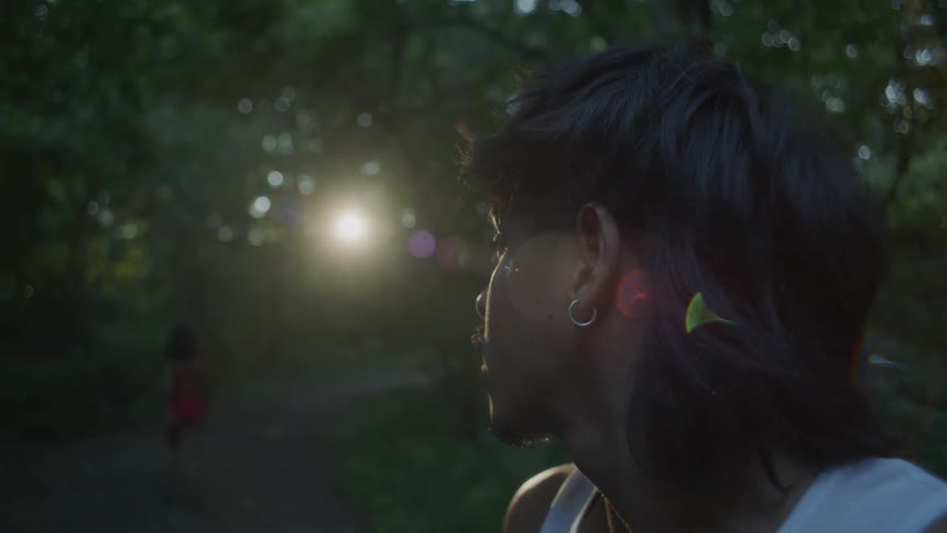 A man standing in a natural setting is looking around then following a woman