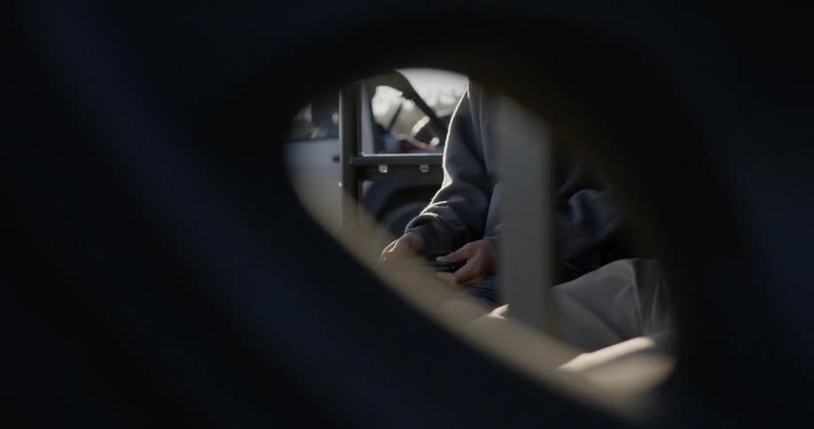 A boy sits with a knife in a truck bed