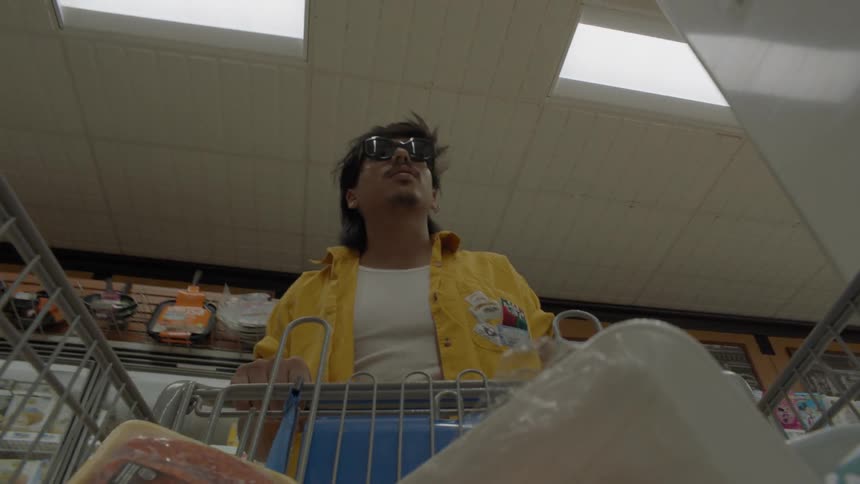 Man wearing sunglasses is pushing a cart in grocery store
