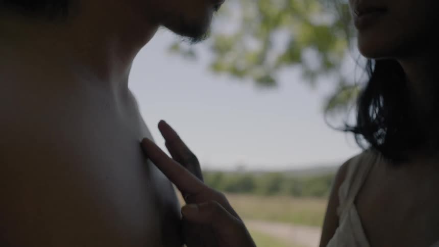 A woman traces a man's chest with her finger