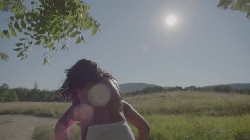 A woman without a shirt is riding on the back of her boyfriend outdoors