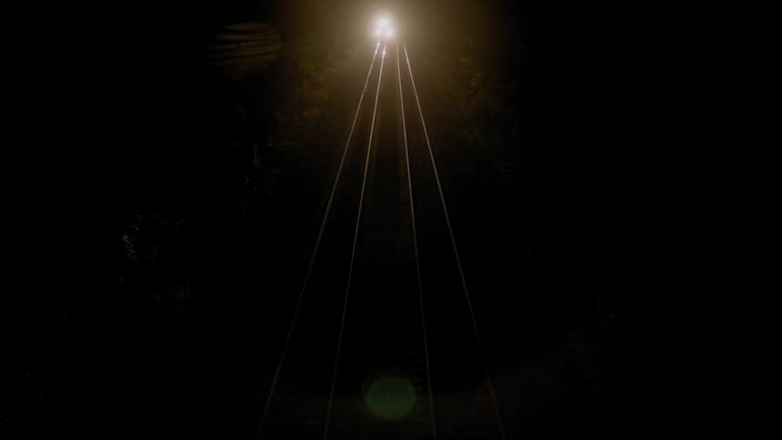 The lights on a train shine on the track at night