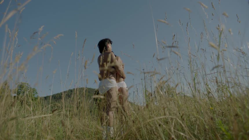 A man and woman hug in a grassy field