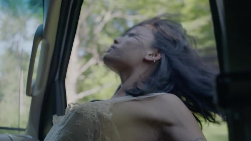 A woman in the passenger seat leans her head out the window