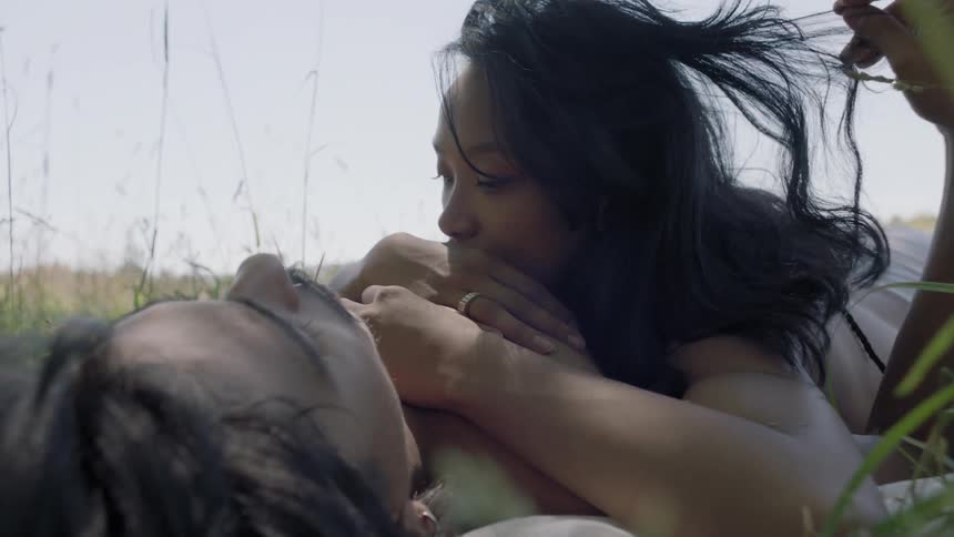 A man and woman are laying in a field of grass