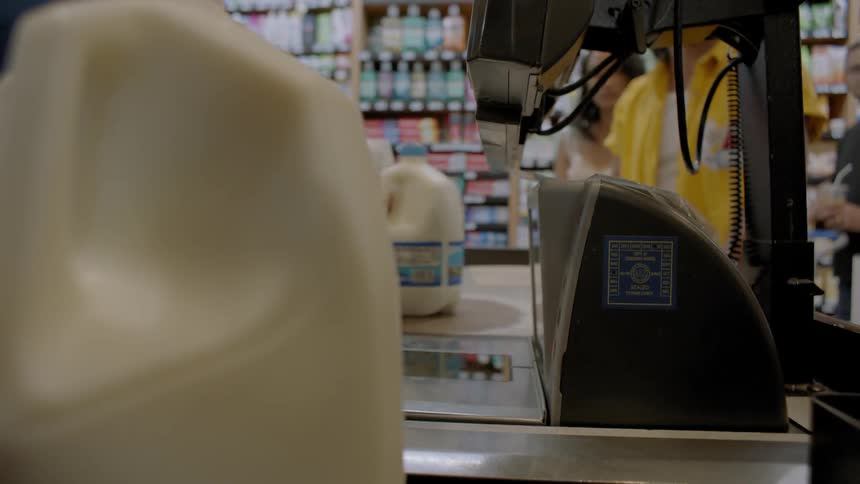 A checker moves milk cartons over the scanner at a store