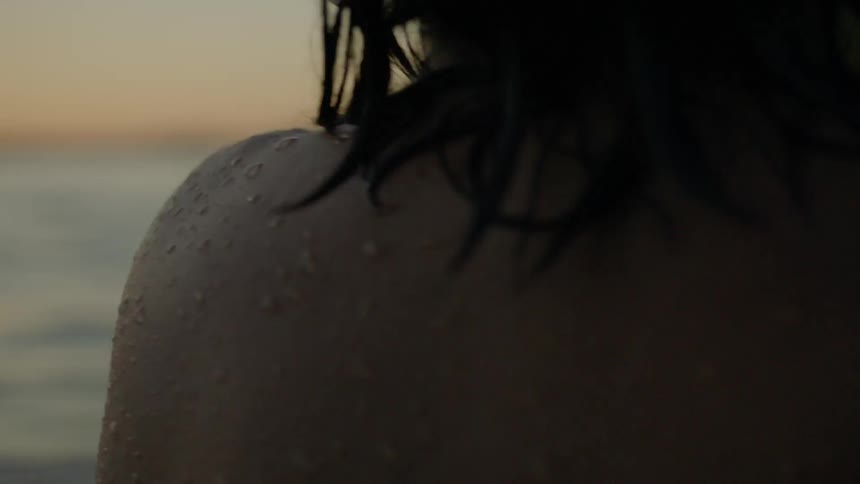 A man without a shirt is walking into a lake
