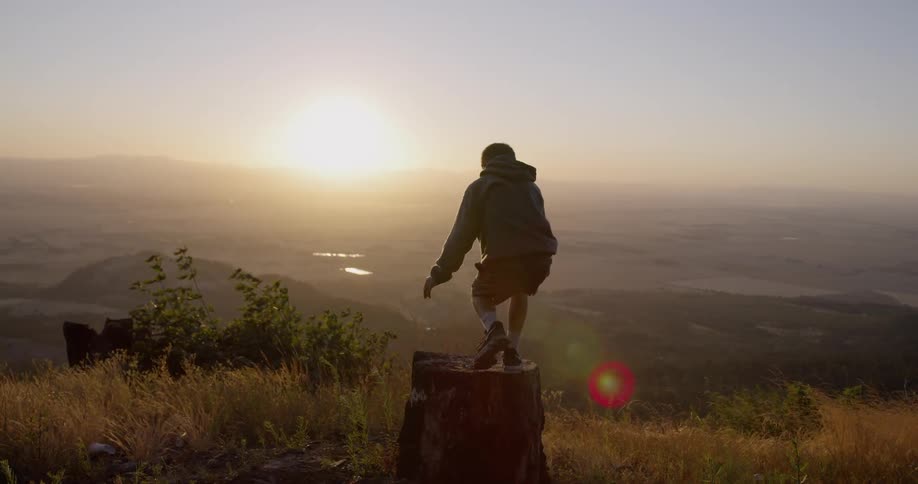 A young boy is running down to a stump overlooking a large valley