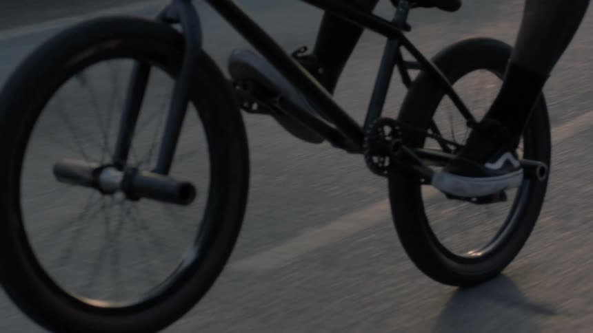 A bike rider pops a wheelie while riding on the street