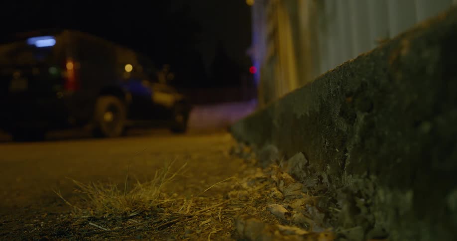 Lights are flashing on a vehicle outside a warehouse at night