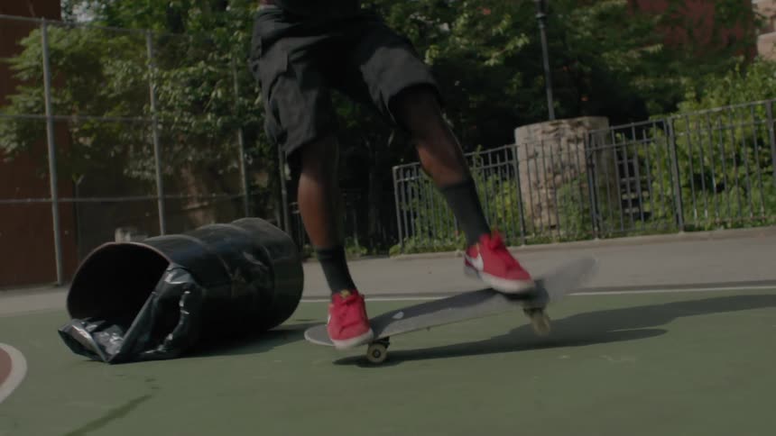 A skateboarder is jumping over a garbage can