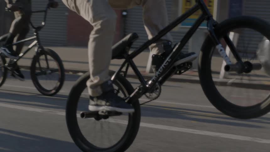 A rider does a wheelie as he rides his bike on a city street with a group of friends