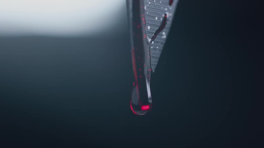 The tip of a knife drips with blood
