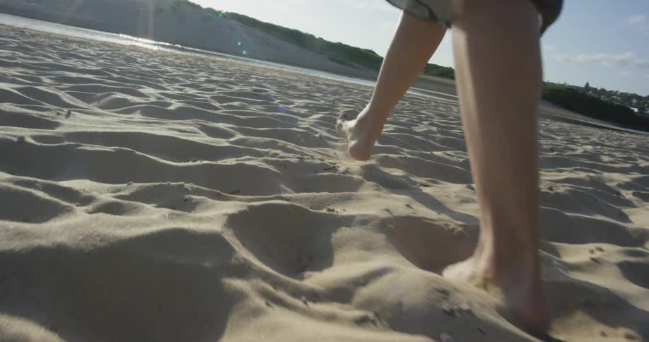A woman walks through a sandy beach