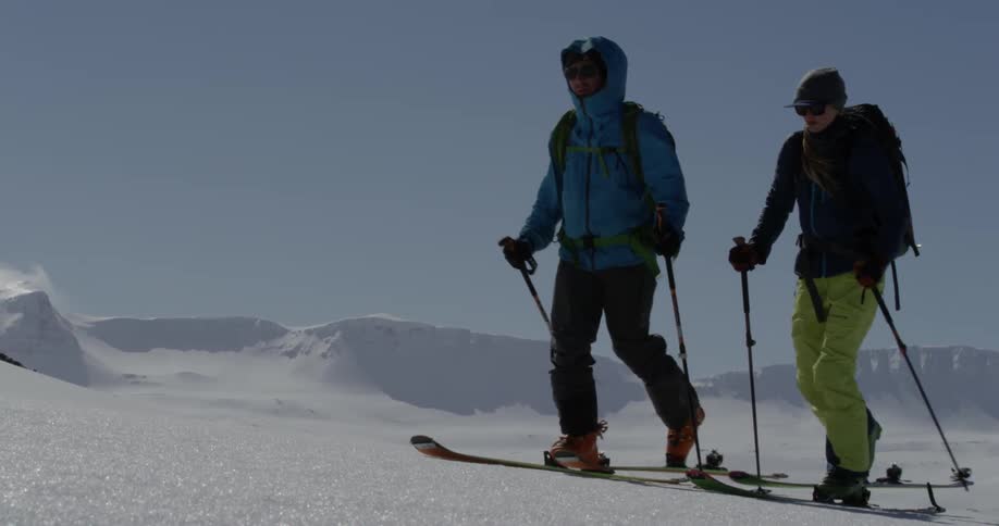 Two people are using skis to get across a snow covered hill