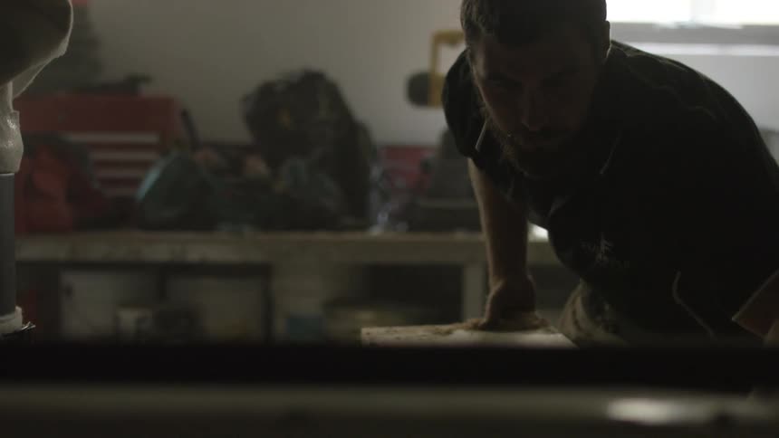 Man brushing shavings off a board