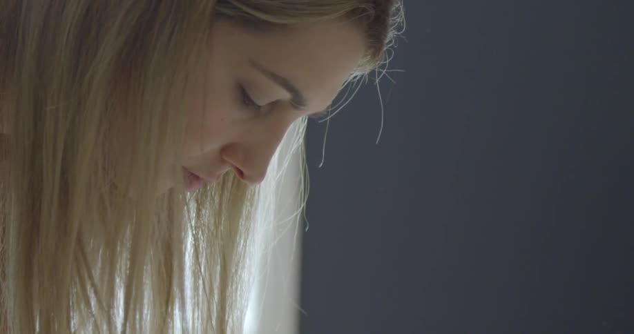 A woman with long dirty blonde hair is bent over at the waist with hair hanging down